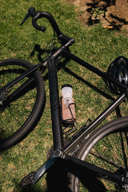 Black bicycle with Sanadora water bottle leaning on grass