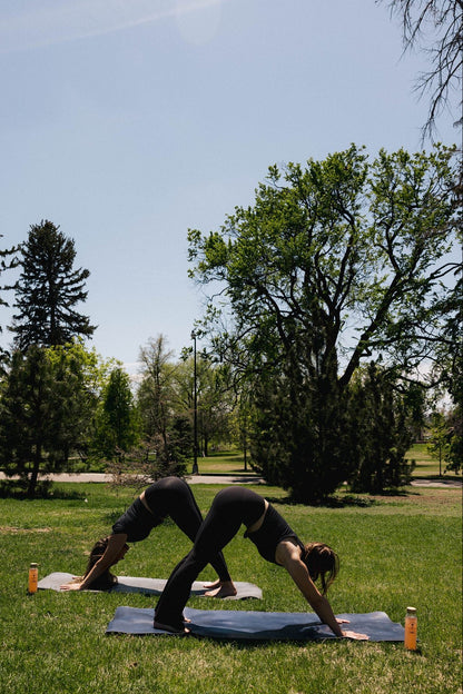 Two people practicing yoga on grass with Creatine Cactus Water