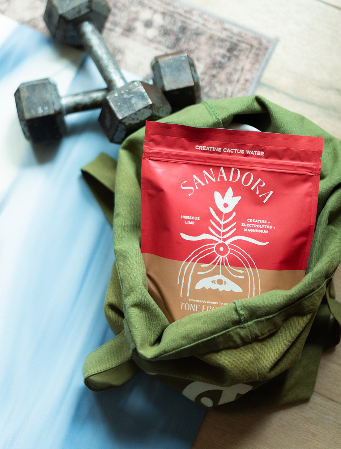 Sanadora Creatine Cactus Water pouch with dumbbells on a workout mat